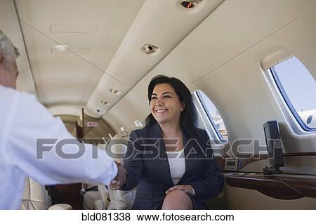Business people shaking hands on private jet View Large Photo Image Stock Photo - Business people shaking hands on private jet. Fotosearch