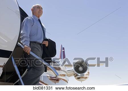 Stock Image - Hispanic businessman exiting private jet. Fotosearch