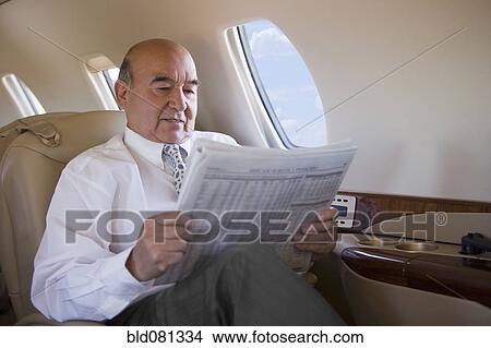 Hispanic businessman reading newspaper on private jet View Large Photo Image Picture - Hispanic businessman reading newspaper on private jet. Fotosearch