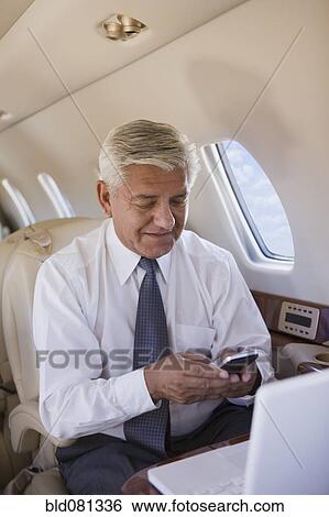 Hispanic businessman using cell phone on private jet View Large Photo Image Stock Photograph - Hispanic businessman using cell phone on private jet. Fotosearch