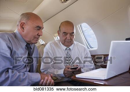 Stock Photography - Hispanic businessmen working on private jet. Fotosearch