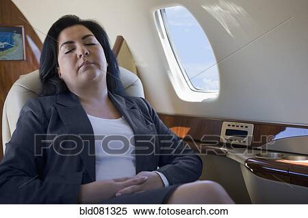 Stock Photography - Hispanic businesswoman sleeping on private jet. Fotosearch
