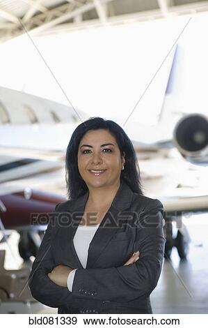 Hispanic businesswoman standing in airplane hangar View Large Photo Image Stock Photo - Hispanic businesswoman standing in airplane hangar. Fotosearch