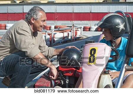 Stock Photo - Hispanic grandfather and grandson on go-cart track. Fotosearch