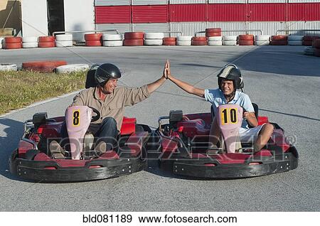 Stock Photo - Hispanic grandfather and grandson on go-cart track. Fotosearch