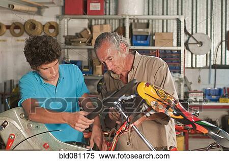 Stock Photography - Hispanic grandfather and grandson working on go-cart. Fotosearch
