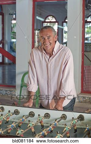 Picture - Hispanic man playing foosball. Fotosearch
