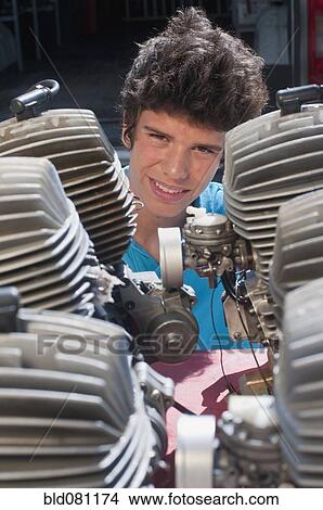 Picture - Hispanic teenager looking at engines. Fotosearch