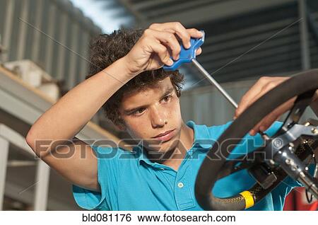 Stock Photograph - Hispanic teenager working on go-cart. Fotosearch