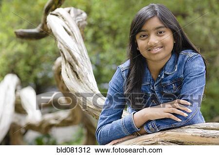 Stock Image - Mixed race girl leaning on tree branch. Fotosearch