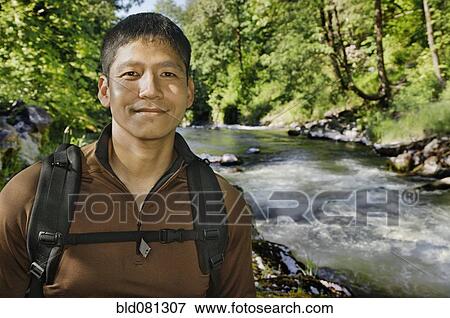 Stock Photo - Mixed race man hiking near river. Fotosearch