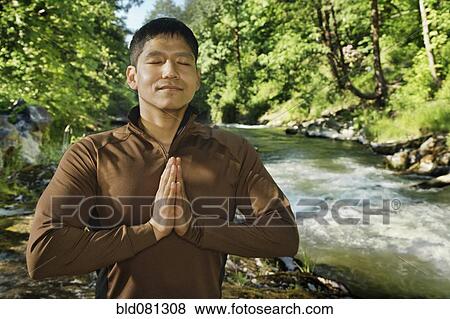 Mixed race man meditating near river View Large Photo Image Stock Photo - Mixed race man meditating near river. Fotosearch