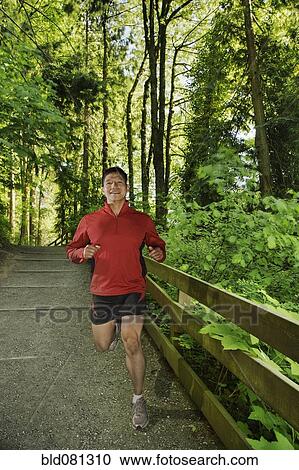Stock Image - Mixed race man running in forest. Fotosearch