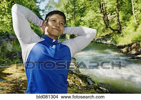 Picture - Mixed race man stretching near river. Fotosearch