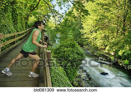 Mixed race runner stretching on walkway near river View Large Photo Image Stock Photo - Mixed race runner stretching on walkway near river. Fotosearch