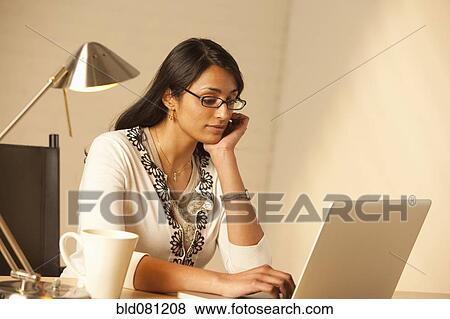 Stock Photo - Mixed race woman typing on laptop. Fotosearch