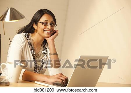Stock Photo - Mixed race woman typing on laptop. Fotosearch