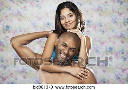Stock Image - Playful Hispanic couple hugging. Fotosearch
