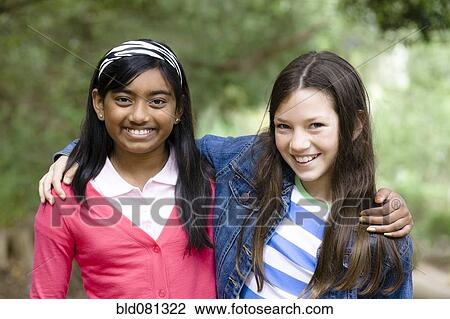 Stock Image - Smiling girls hugging outdoors. Fotosearch