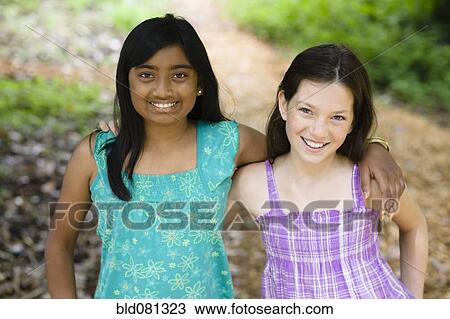 Stock Image - Smiling girls hugging outdoors. Fotosearch