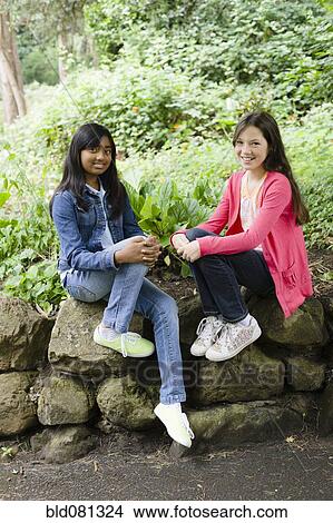 Picture - Smiling girls sitting together outdoors. Fotosearch