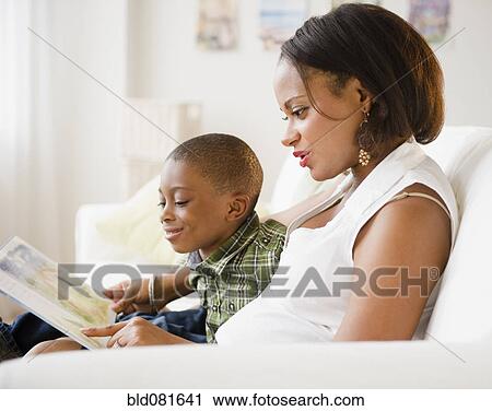 Black mother and son reading book on living room sofa View Large Photo Image Stock Image - Black mother and son reading book on living room sofa. Fotosearch