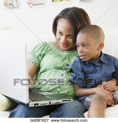 Black mother and son using laptop on sofa View Large Photo Image Stock Photo - Black mother and son using laptop on sofa. Fotosearch