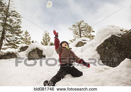 Stock Photograph - Boy throwing snowball overhead. Fotosearch