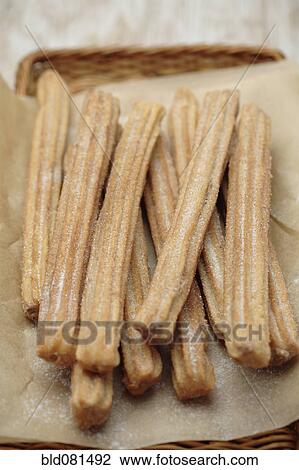 Stock Image - Close up of churros in basket. Fotosearch