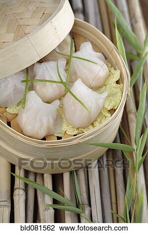Stock Image - Close up of dim sum dumplings in bamboo basket. Fotosearch