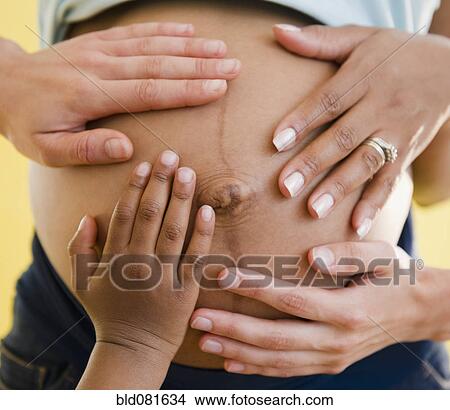 Picture - Close up of hands on pregnant woman's stomach. Fotosearch