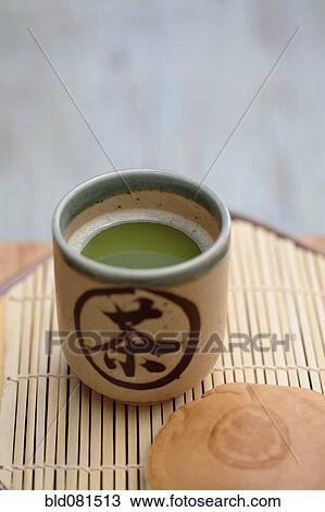 Stock Image - Close up of Japanese green Matcha tea and red bean pastry. Fotosearch