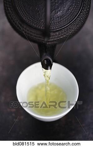 Stock Photography - Close up of Japanese green tea being poured from teapot into cup. Fotosearch