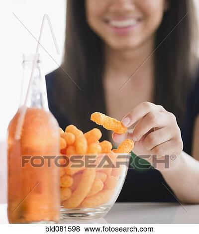 Close up of mixed race teenage girl eating cheese puffs View Large Photo Image Stock Photo - Close up of mixed race teenage girl eating cheese puffs. Fotosearch