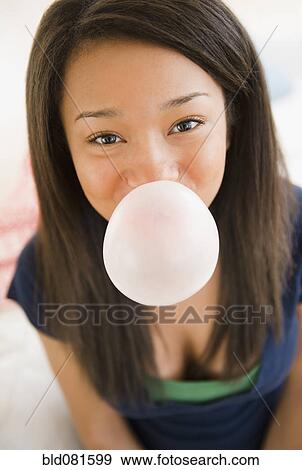Stock Photo - Close up of mixed race teenage girl blowing bubble with gum. Fotosearch