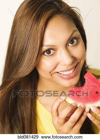 Close up of smiling Hispanic woman eating watermelon View Large Photo Image Stock Photo - Close up of smiling Hispanic woman eating watermelon. Fotosearch