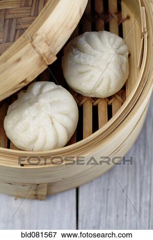 Stock Photo - Close up of steamed dim sum pork buns in bamboo basket. Fotosearch