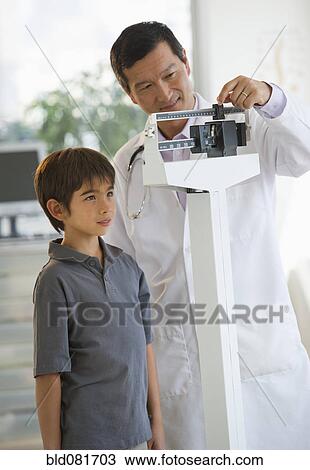 Doctor weighing boy on scale View Large Photo Image Stock Image - Doctor weighing boy on scale. Fotosearch