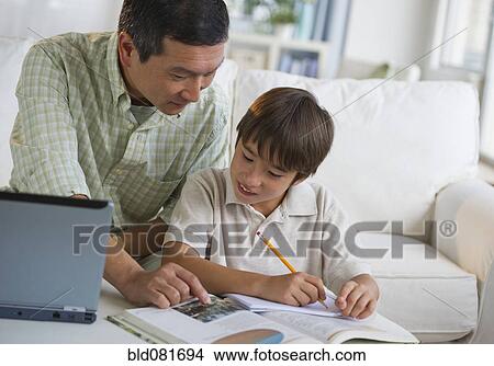 Father helping son with homework in living room View Large Photo Image Picture - Father helping son with homework in living room. Fotosearch