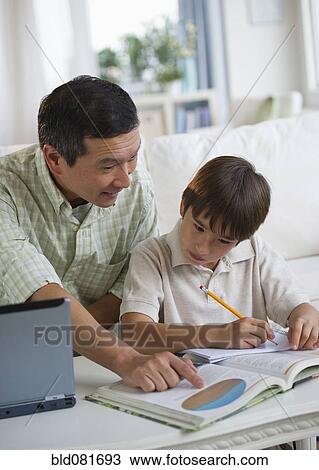 Father helping son with homework in living room View Large Photo Image Stock Image - Father helping son with homework in living room. Fotosearch