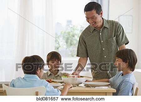 Father serving dinner to sons at table View Large Photo Image Stock Photo - Father serving dinner to sons at table. Fotosearch