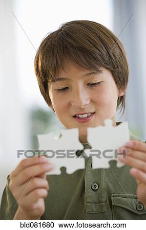 Mixed race boy connecting jigsaw pieces View Large Photo Image Stock Image - Mixed race boy connecting jigsaw pieces. Fotosearch