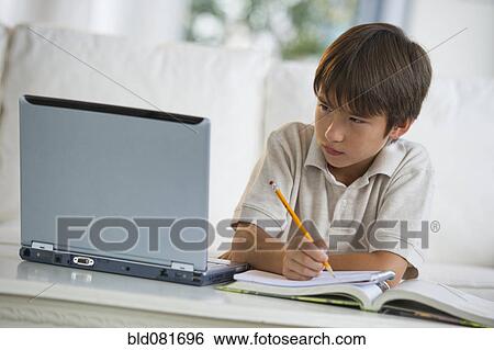 Stock Photograph - Mixed race boy doing homework and looking at laptop. Fotosearch