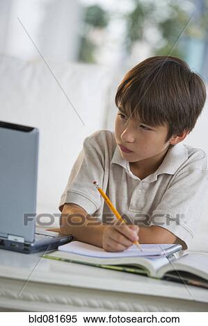 Stock Photography - Mixed race boy doing homework and looking at laptop. Fotosearch