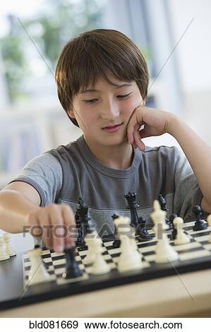 Stock Photo - Mixed race boy playing chess. Fotosearch
