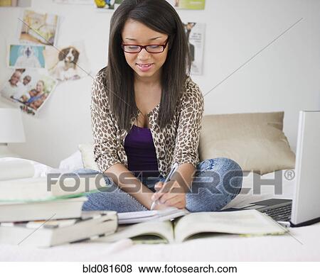 Mixed race teenage girl doing homework on bed View Large Photo Image Stock Photo - Mixed race teenage girl doing homework on bed. Fotosearch