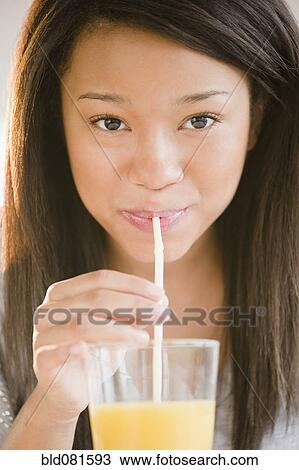 Mixed race teenage girl sipping orange juice with straw View Large Photo Image Stock Image - Mixed race teenage girl sipping orange juice with straw. Fotosearch