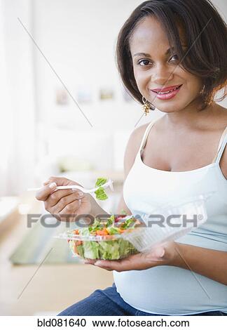 Pregnant Black woman eating salad View Large Photo Image Stock Image - Pregnant Black woman eating salad. Fotosearch