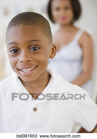 Smiling Black boy with mother in background View Large Photo Image Stock Image - Smiling Black boy with mother in background. Fotosearch