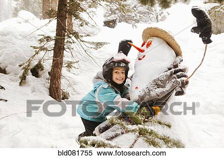 Stock Photography - Smiling girl hugging snowman. Fotosearch